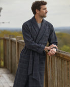 Bonsoir of London Men’s Thomas Check Silk-Lined Wool Robe, featuring a charcoal grey wool fabric with subtle teal green check design, silk lining, shawl collar, three pockets, turn-back cuffs and wide tie belt, full body shot on a model.
